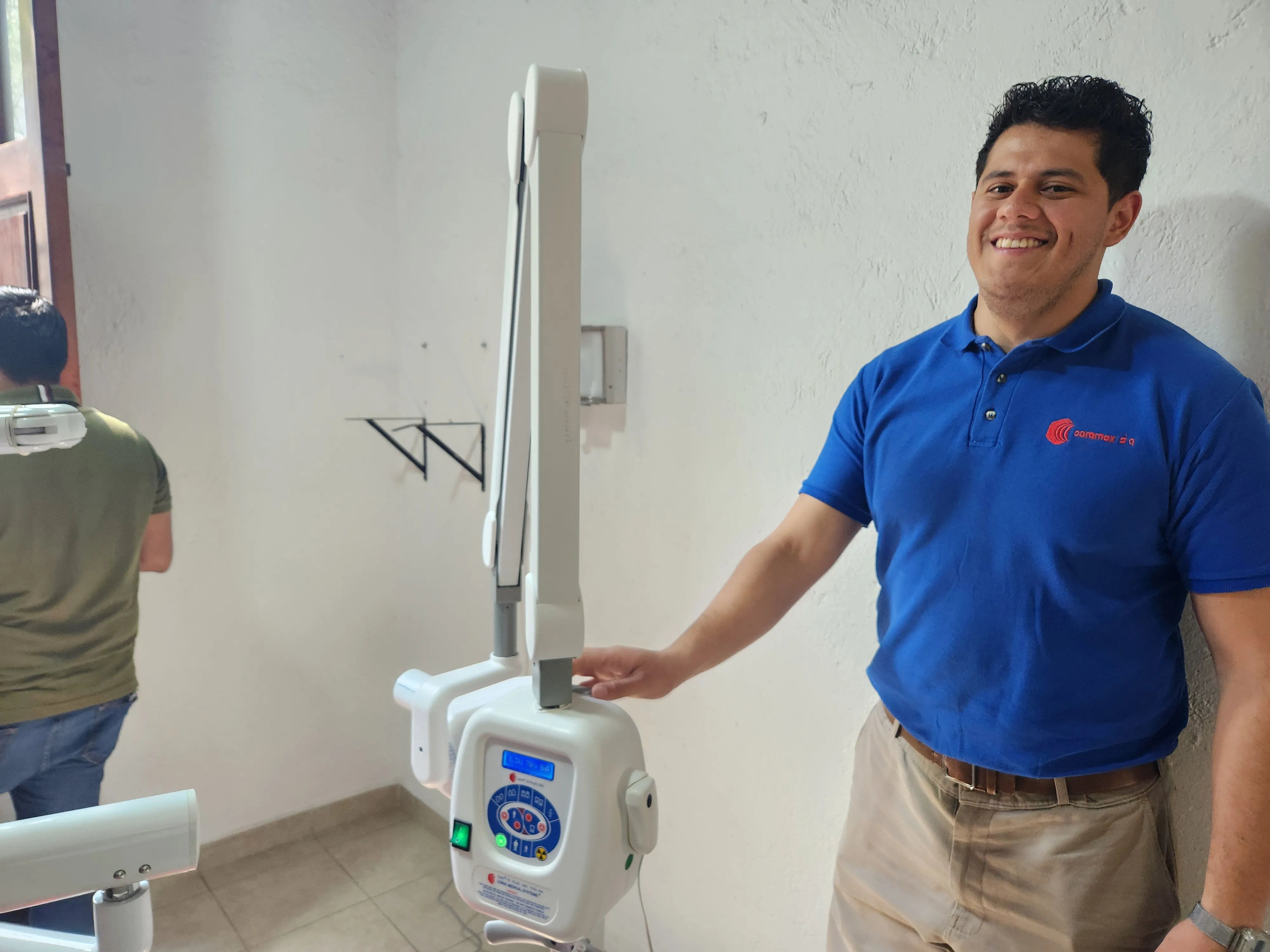 Hombre con playera de la marca Corix, demostrando el funcionamiento adecuado de un equipo de rayos X para la protección radiológica.